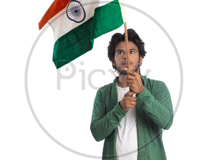 A Young Indian man Holding  Indian National Flag ( Tri Color )  In Hands And Posing Over a White Isolated Background