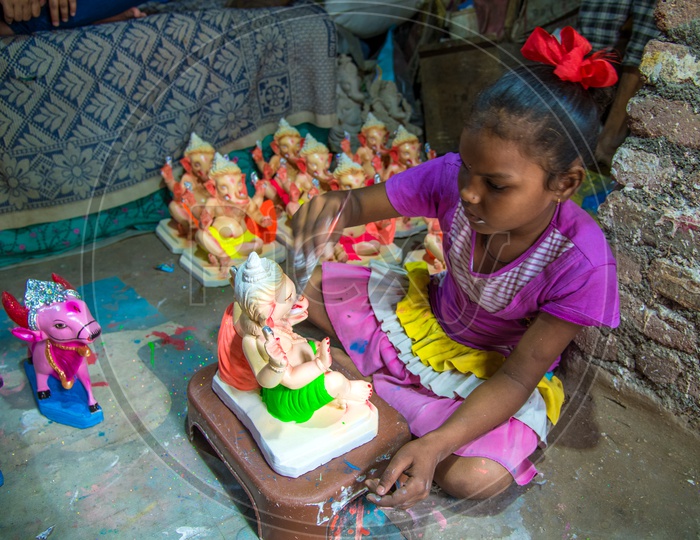 A Small Girl Or Child  Working In Ganesh Idols Making Workshop Painting The Ganesh Idols
