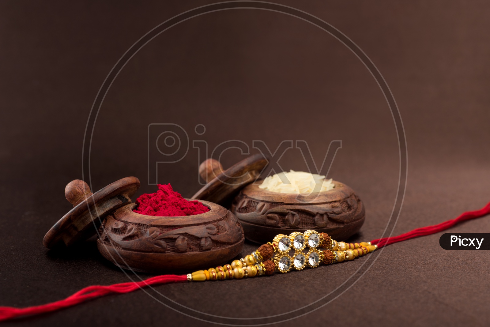 Raksha Bandhan background with an elegant Rakhi, Rice Grains and Kumkum.