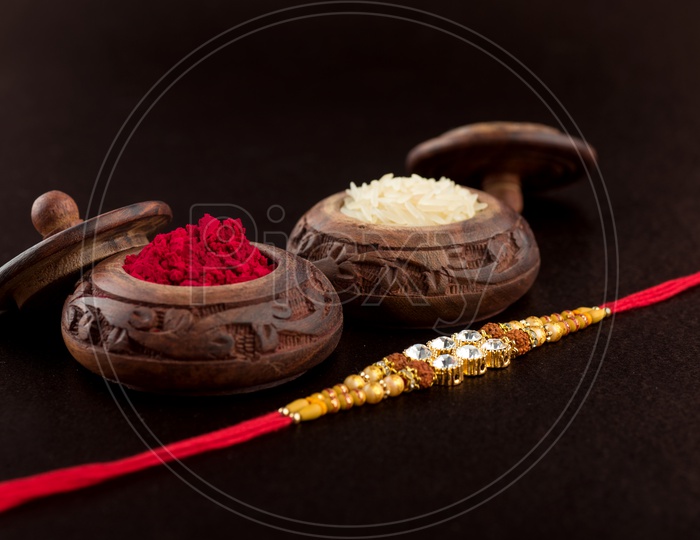 Raksha Bandhan background with an elegant Rakhi, Rice Grains and Kumkum