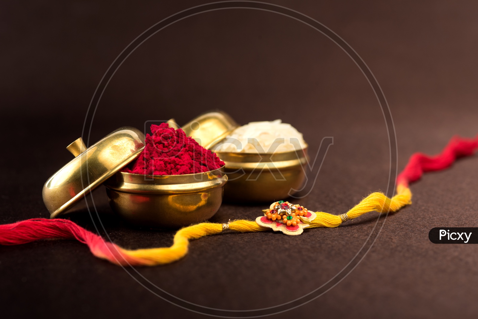 Raksha Bandhan background with an elegant Rakhi, Rice Grains and Kumkum.