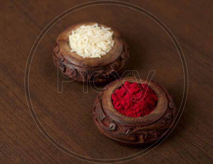 Kumkum And Rice Grains In an elegant Wooden Pots on an Wooden Background