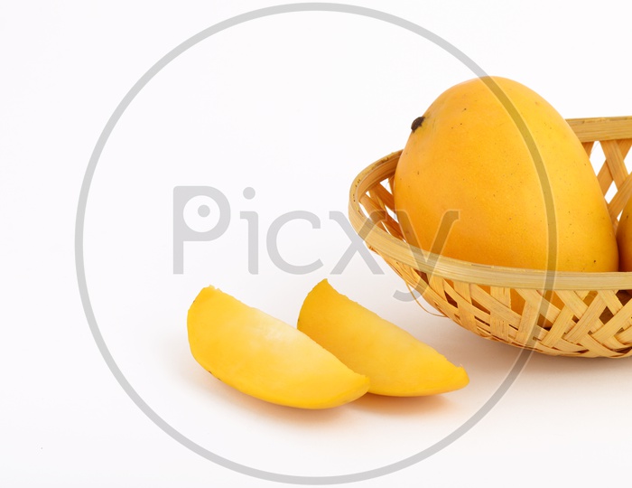 Fresh Ripen Mangoes And Mango Slices In a Wooden Weaved Basket  on an Isolated White  Background