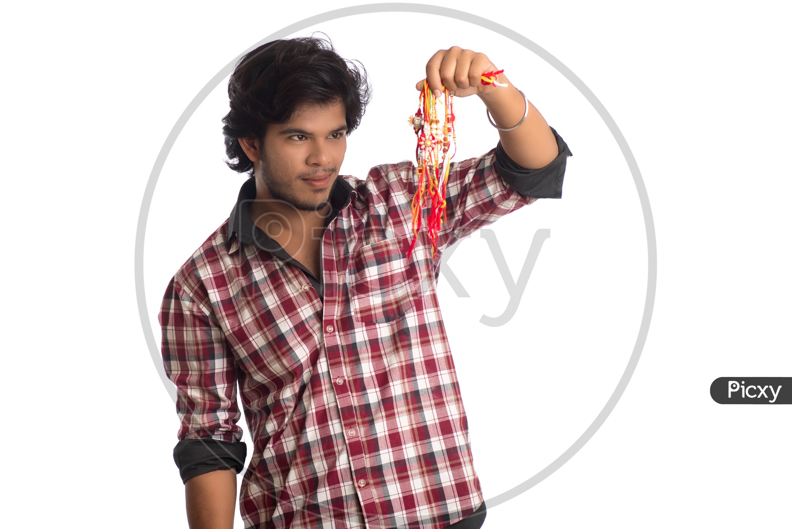 A Young Indian Man Holding Elegant Rakhis In Hand Posing Over a White Background