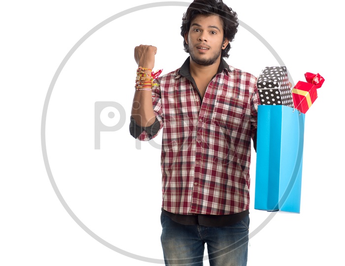 Indian Young Man Showing  Rakhi Tied Hand And  with  a Gift Box For his Sister  On an  Isolated White Background