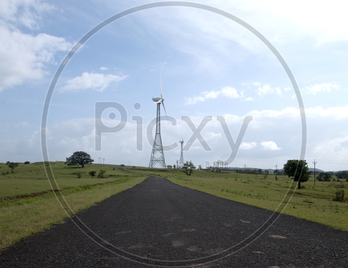 A Road Leading To a Wind Mill On Green Terrain High Land