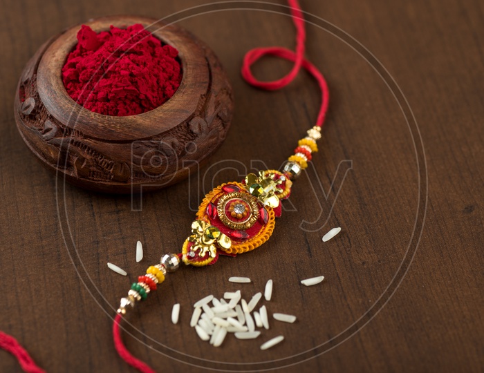 Indian festival: Raksha Bandhan background with an elegant Rakhi, Rice Grains and Kumkum.
