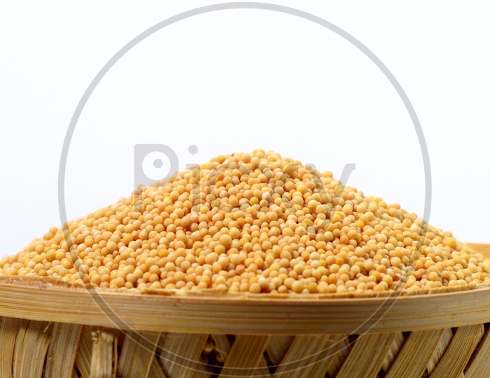 Yellow Mustard Seeds In a Wooden Weaved Basket  On an Isolated White Background