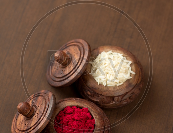 Kumkum And Rice Grains In an elegant Wooden Pots on an Wooden Background
