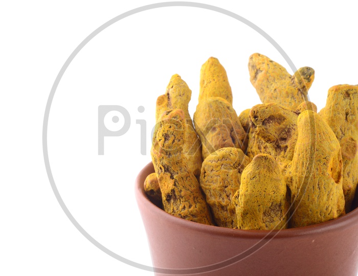 Dry Turmeric Roots Or Barks  In a Clay pot  On an Isolated White Background