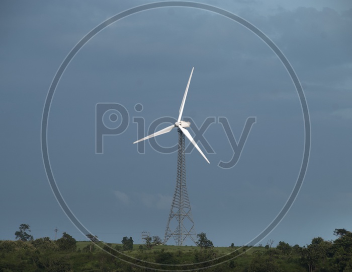 Wind Mill On a Green Terrain High Land With Blue Sky In  Background