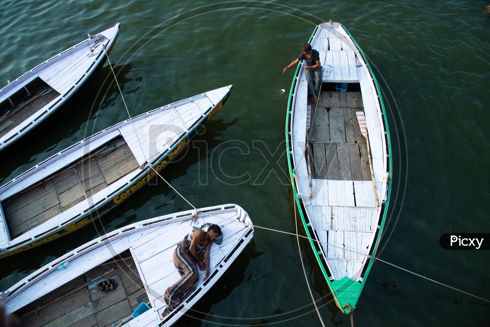 A Boat Driver Or Helmsman  Sleeping On Boat  by Anchoring at Ghats In  Varanasi