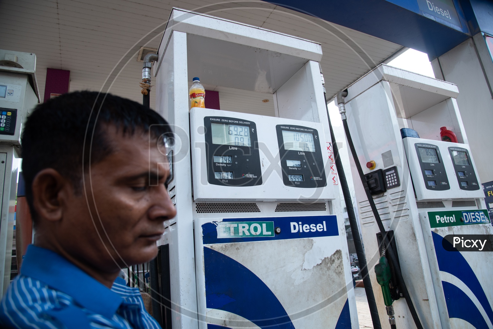 Petrol Station Worker With Fuel Teller Machine  In Background in a Fuel Station Or Petrol Station Or Petrol Bunk  in India With Fuel Pricing In  Display