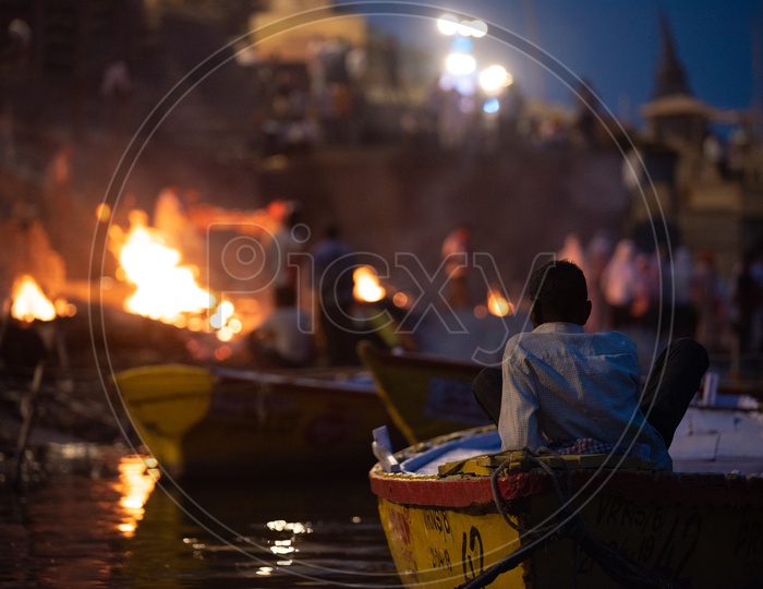 A Boat Rider Or Helmsman  At Manikarnika Ghat Watching The Burying of Dead Bodies  In Varanasi