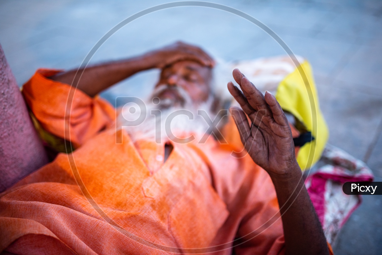 An Indian Baba Or Sadhu  Sleeping And Raising His Hand As a Blessing For The  People  At Varanasi