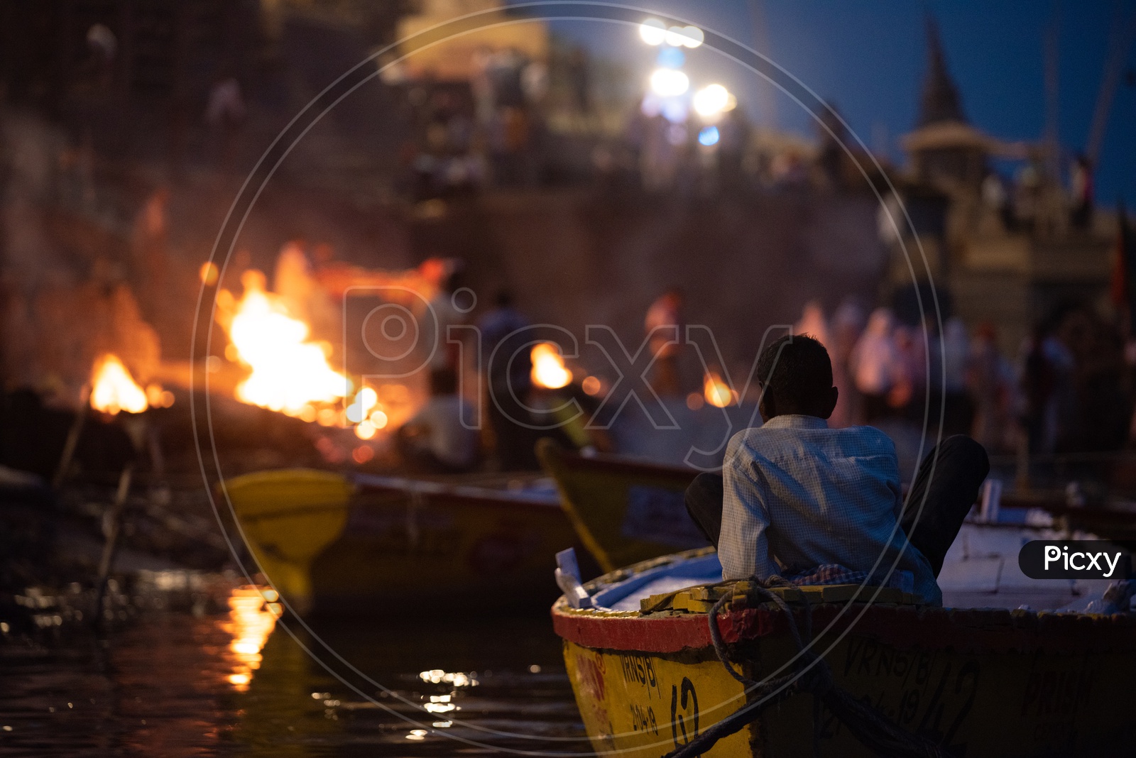 A Boat Rider Or Helmsman  At Manikarnika Ghat Watching The Burying of Dead Bodies  In Varanasi