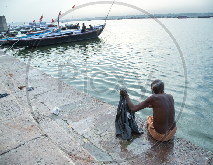 An Oldman Washing Clothes On The River Bank Of Ganga At Ghats of Varanasi