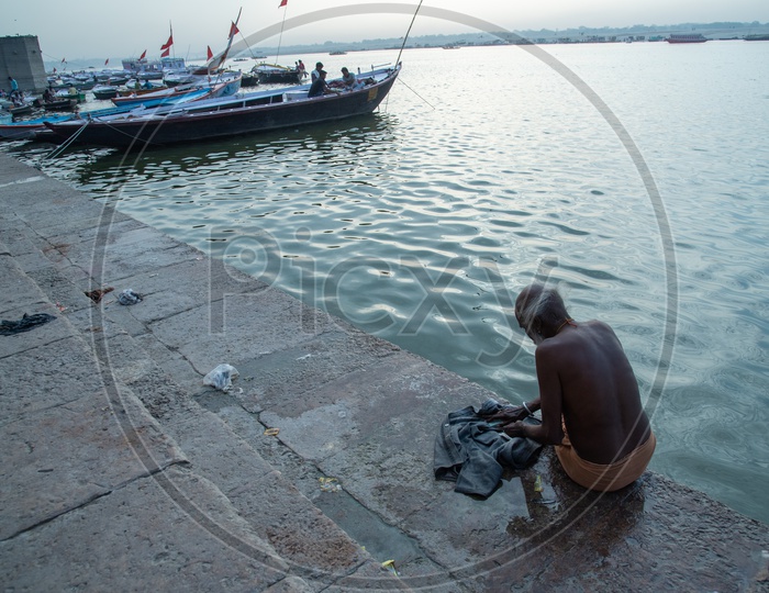 An Oldman Washing Clothes On The River Bank Of Ganga At Ghats of Varanasi