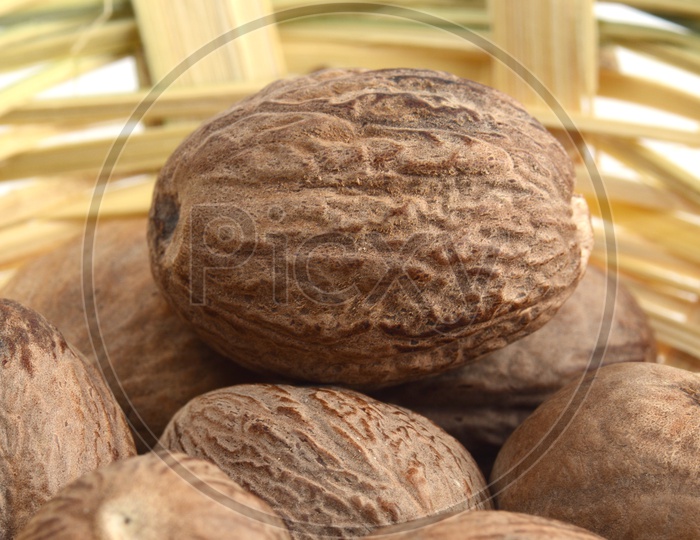 Indian Spice Nutmeg In a Wooden Weaved Basket  On an Isolated White Background