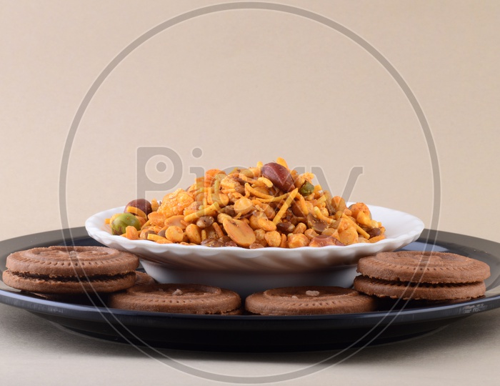 Indian Salty Depp Fried Snack Chivda Or Mixture  And Biscuits On a Plate over an Isolated Background