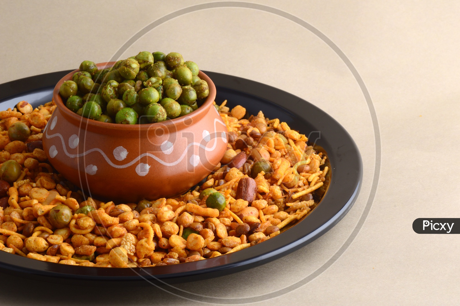 Indian Snacks, Salty Deep Fried Chivda or Mixture  Along With Fried Salty Green Peas in a Clay Pot   on an Isolated Background