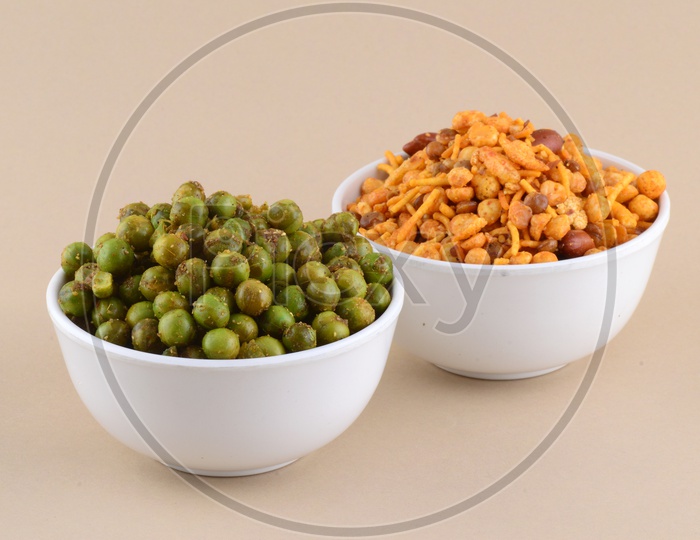 Indian Snack Salty Deep Fried Chivda Or  Mixture and Deep Fried Masala Green Peas  In a White Bowl On an Isolated Background