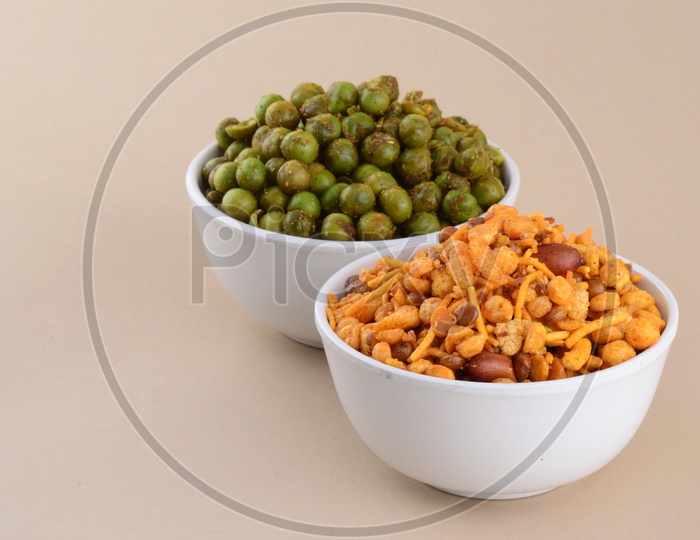 Indian Snack Salty Deep Fried Chivda Or  Mixture and Deep Fried Masala Green Peas  In a White Bowl On an Isolated Background