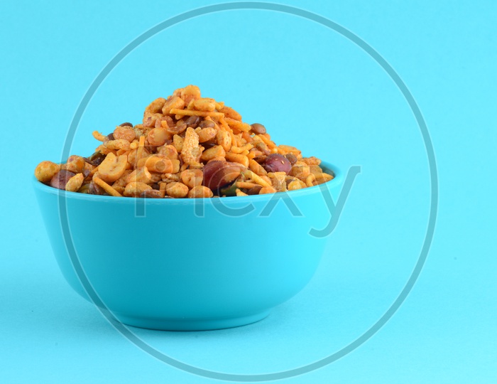 Indian Snack , Salty Deep Fried Chivda Or Mixture In a  Blue Bowl On an Isolated Blue   Background
