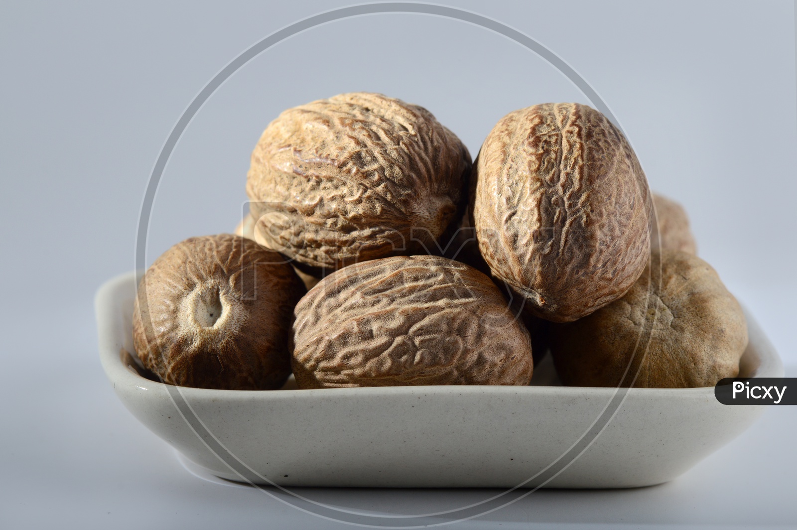 Image of Indian Spice Nutmeg in a Bowl On an Isolated White Background