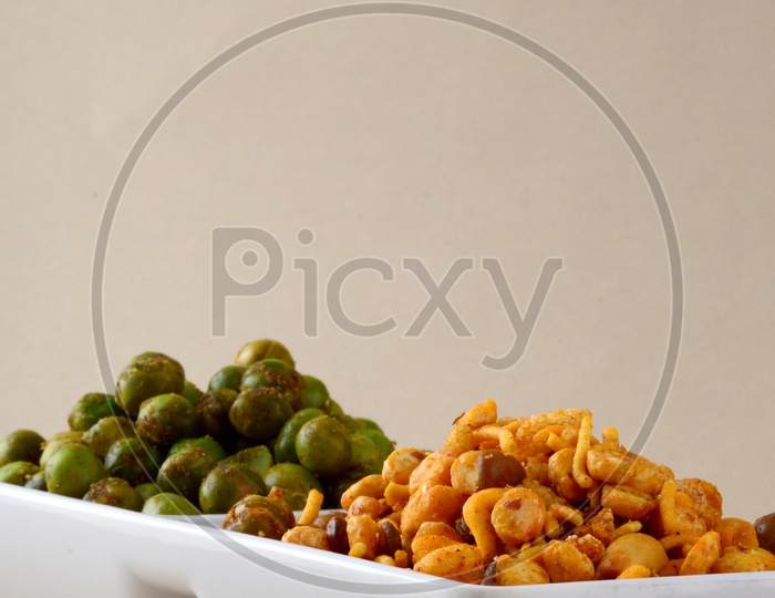 Indian Snack Deep Fried Salty Mixture Or Chivda And Spicy Fried Green Peas Or Masala  Chatpata  matar  in Bowls On an Isolated Background