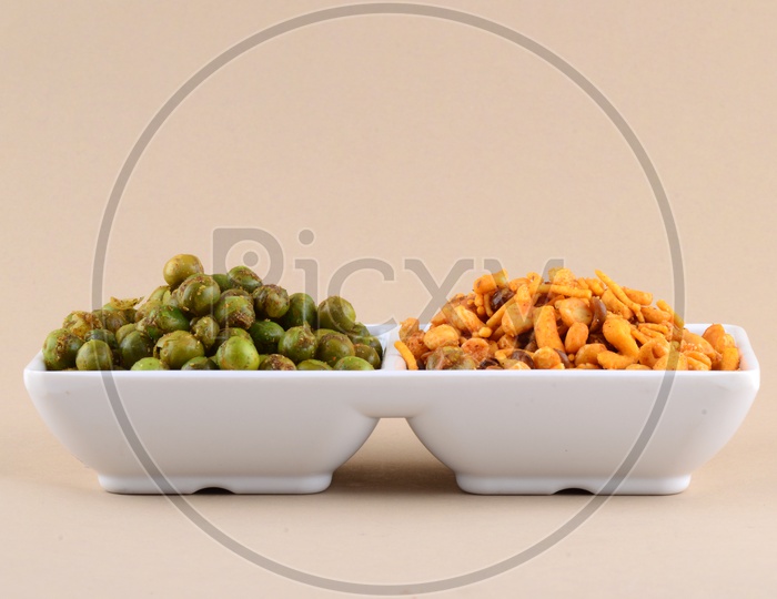 Indian Snack Deep Fried Salty Mixture Or Chivda And Spicy Fried Green Peas Or Masala  Chatpata  matar  in Bowls On an Isolated Background