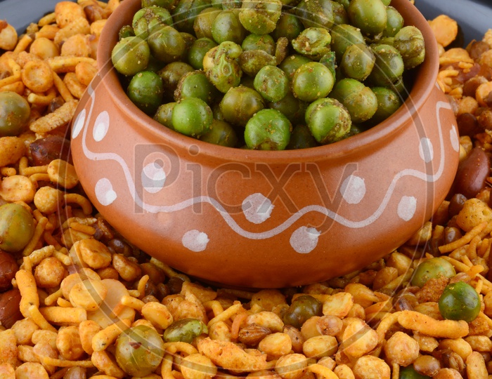 Indian Snacks, Salty Deep Fried Chivda or Mixture  Along With Fried Salty Green Peas in a Clay Pot