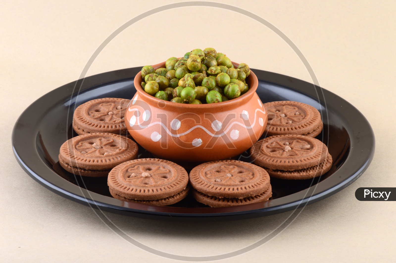 Image of Deep Fried Salty Green Peas In a Clay Bowl And Creme Biscuits on an Plate Over an