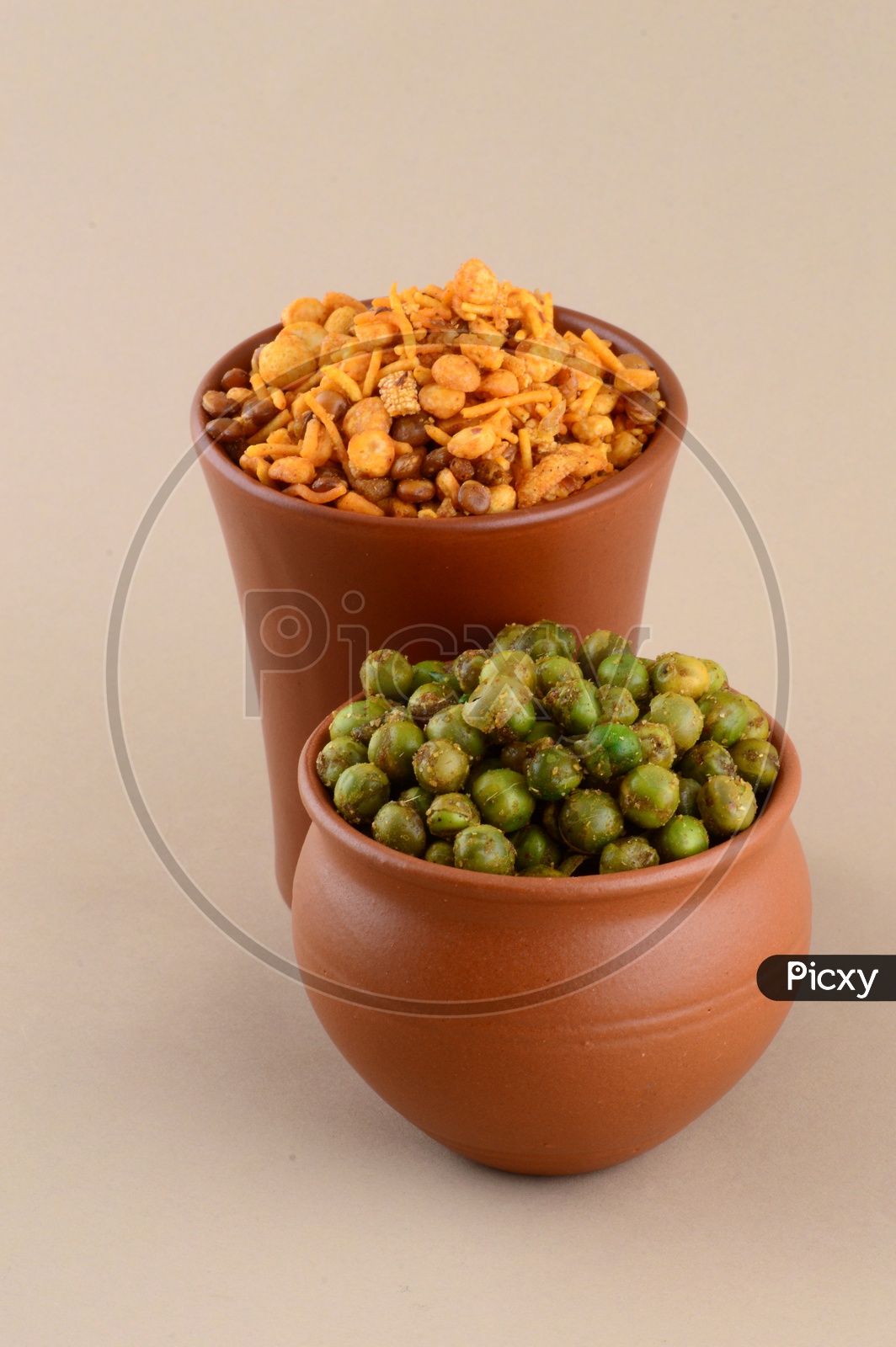 Indian Snack Salty Deep Fried Chivda Or  Mixture and Deep Fried Masala Green Peas  In a Clay Pots  On an Isolated Background