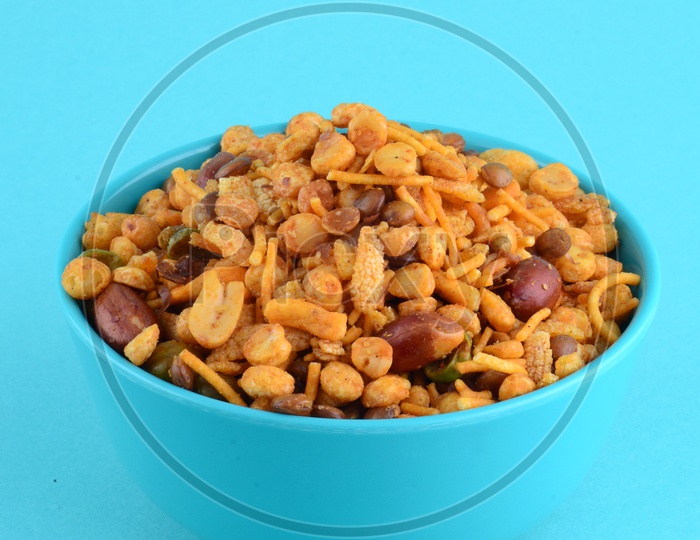 Indian Snack , Salty Deep Fried Chivda Or Mixture In a Blue Bowl On an Isolated Blue Background
