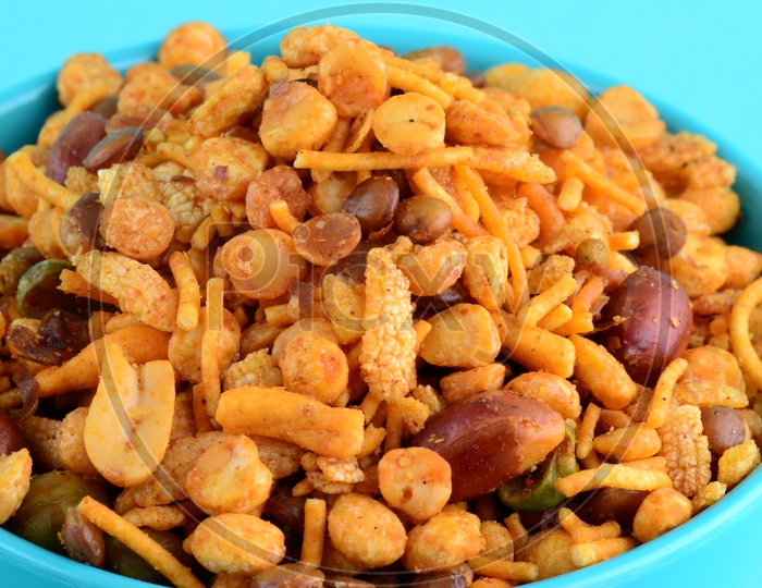 Indian Snack , Salty Deep Fried Chivda Or Mixture In a Blue Bowl On an Isolated Blue Background