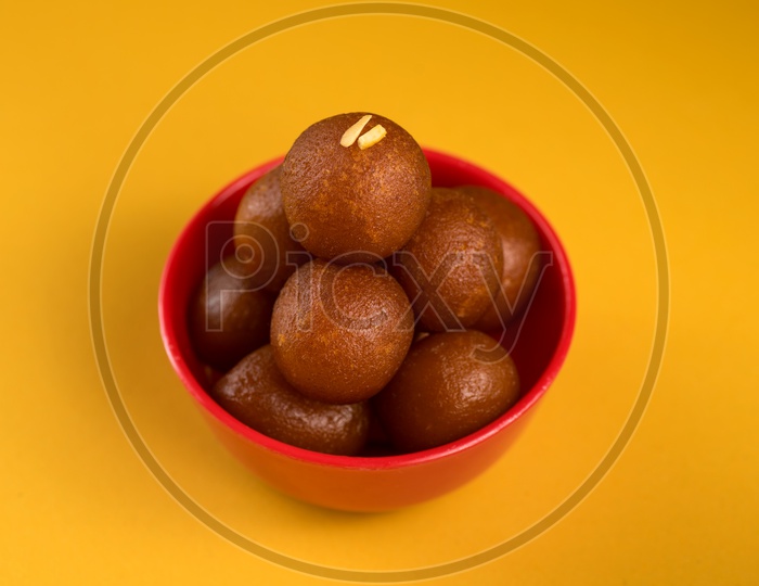 Indian Sweet or Dessert or Savoury Gulab Jamun  in a Bowl On an Isolated Yellow   Background