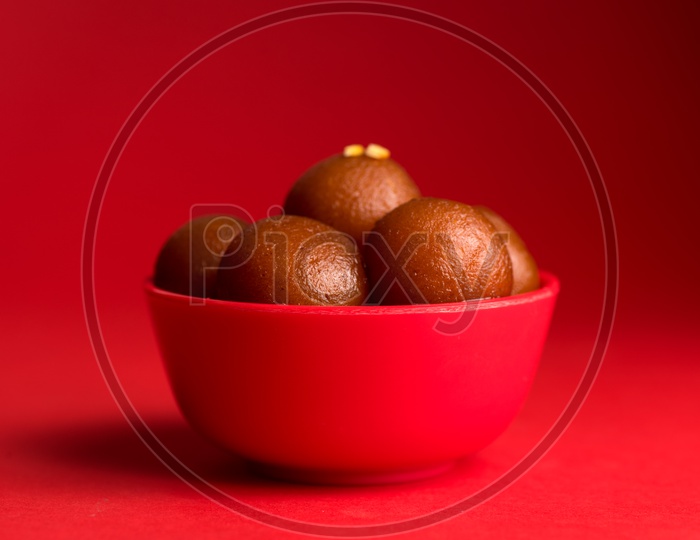 Indian Sweet or Dessert or Savoury Gulab Jamun  in a Bowl On an Isolated Red Background