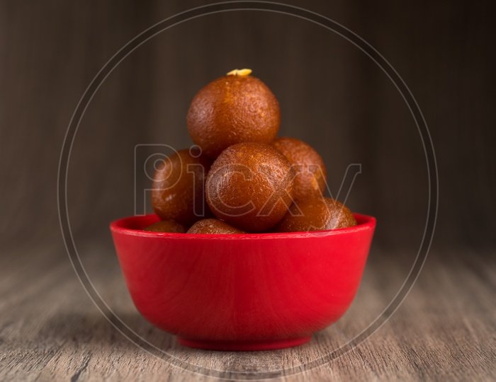 Indian Sweet or Dessert or Savoury Gulab Jamun  in a Bowl On an Isolated Wooden  Background