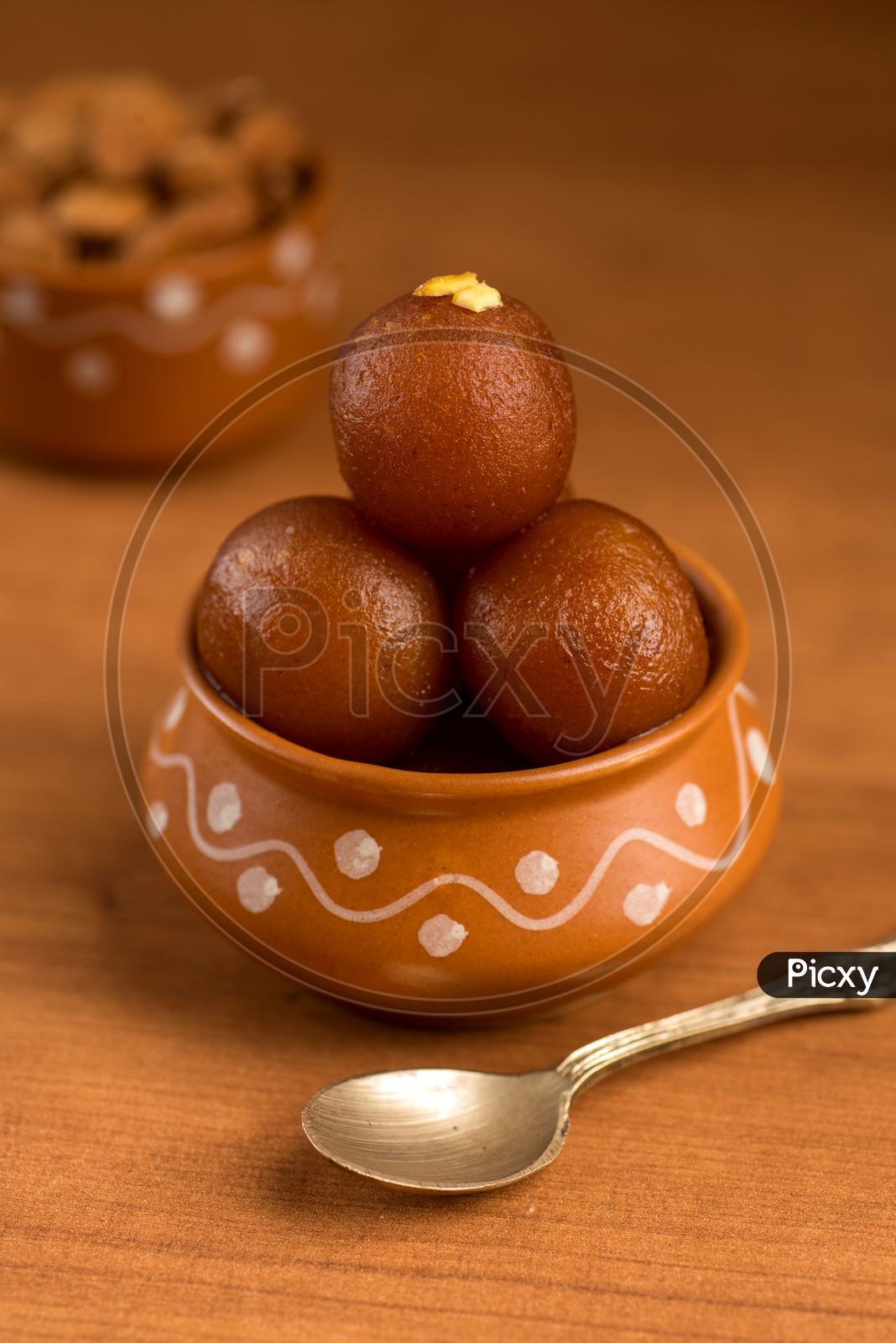 Indian Sweet or Dessert or Savoury Gulab Jamun  Served in an Elegant  Clay  Pot   On an Isolated Wooden Background