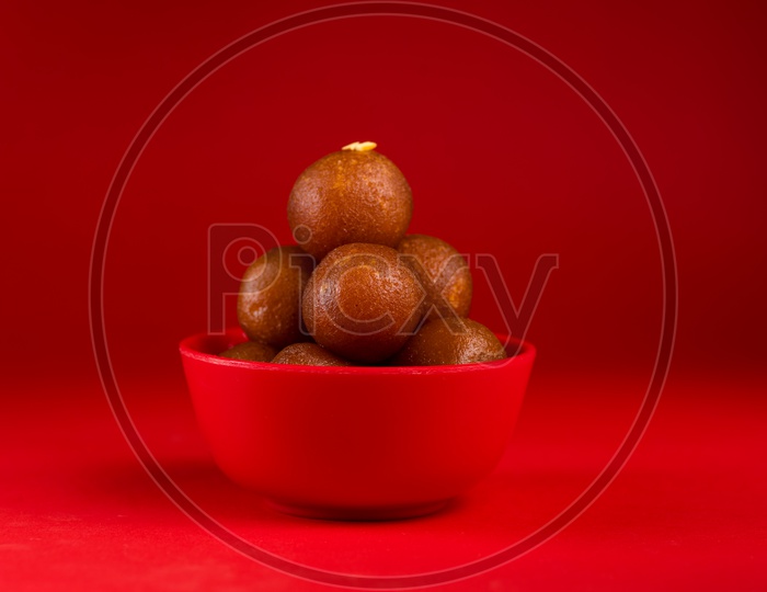 Indian Sweet or Dessert or Savoury Gulab Jamun  in a Bowl On an Isolated Red  Background