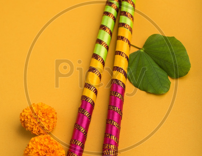 Indian Festival Dussera or Navrathri Symbolic Representation With Dandiya Sticks , Mari Gold Flowers And Golden Leaf ( Bauhinia Racemosa )