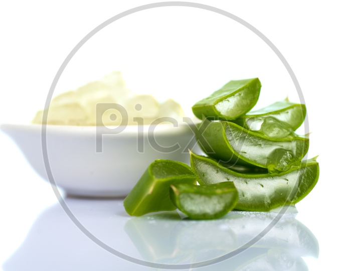 Extracted Aloe Vera Gel In an White Bowl Along With Aloe Vera Pieces on an Isolated White Background