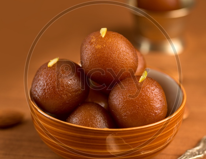 Indian Sweet or Dessert or Savoury Gulab Jamun  Served in a Wooden Bowl    On an Isolated Wooden Background