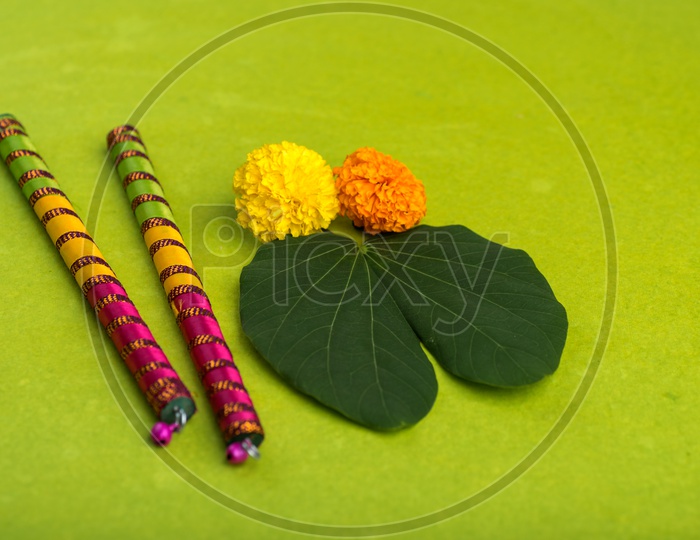 Indian Festival Dussera or Navrathri Symbolic Representation With Dandiya Sticks , Mari Gold Flowers And Golden Leaf ( Bauhinia Racemosa ) on an Isolated Background