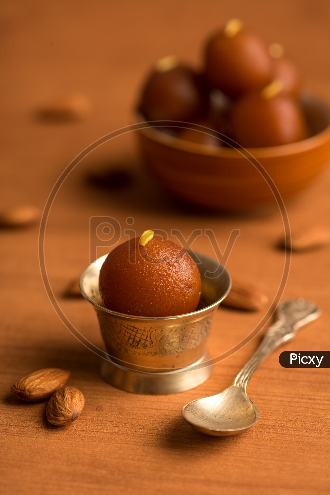 Indian Sweet or Dessert or Savoury Gulab Jamun  Served in an Elegant Bowl Along With a Spoon On an Isolated Wooden Background