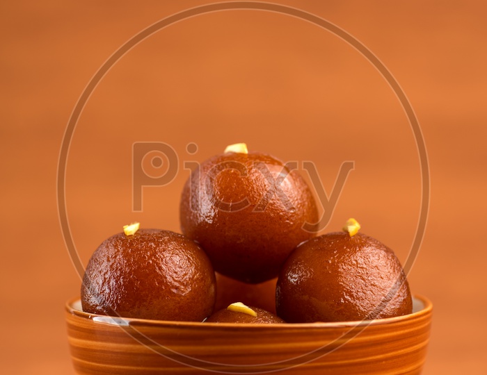 Indian Sweet or Dessert or Savoury Gulab Jamun  Served in a Wooden Bowl  On an Isolated Wooden Background