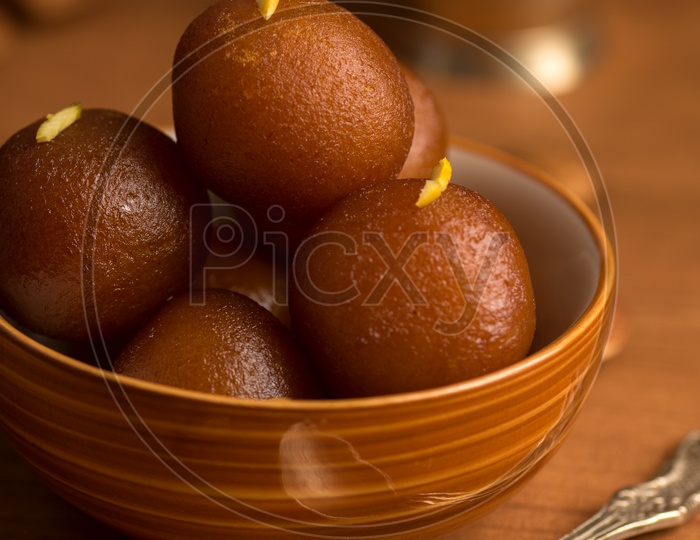 Indian Sweet or Dessert or Savoury Gulab Jamun  Served in a Wooden Bowl    On an Isolated Wooden Background