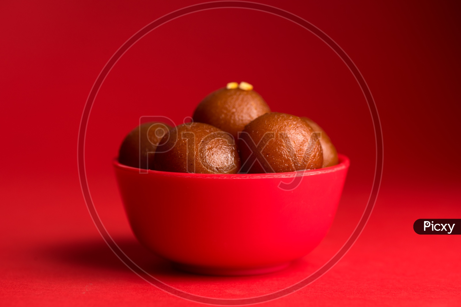 Indian Sweet or Dessert or Savoury Gulab Jamun  in a Bowl On an Isolated Red Background