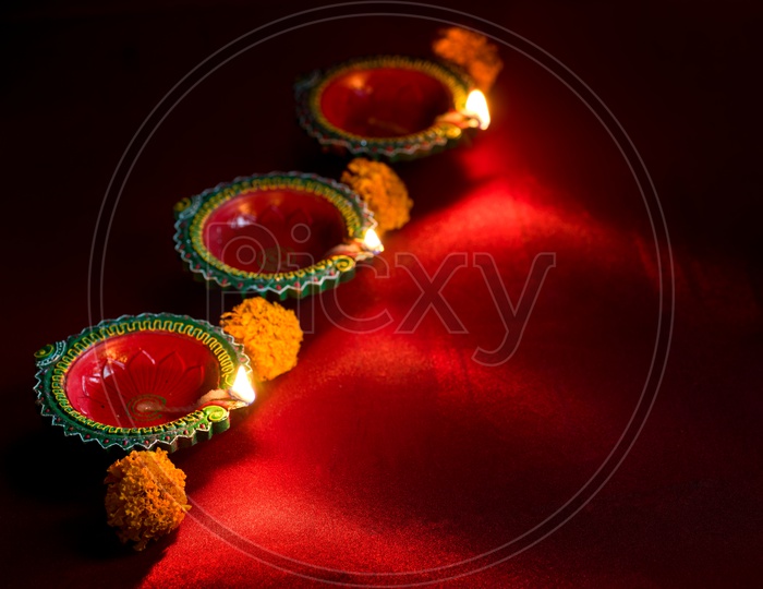 Indian Traditional Diwali Diyas Lighted on an Isolated Red Background For Diwali Wishes Or  Festival Message Template